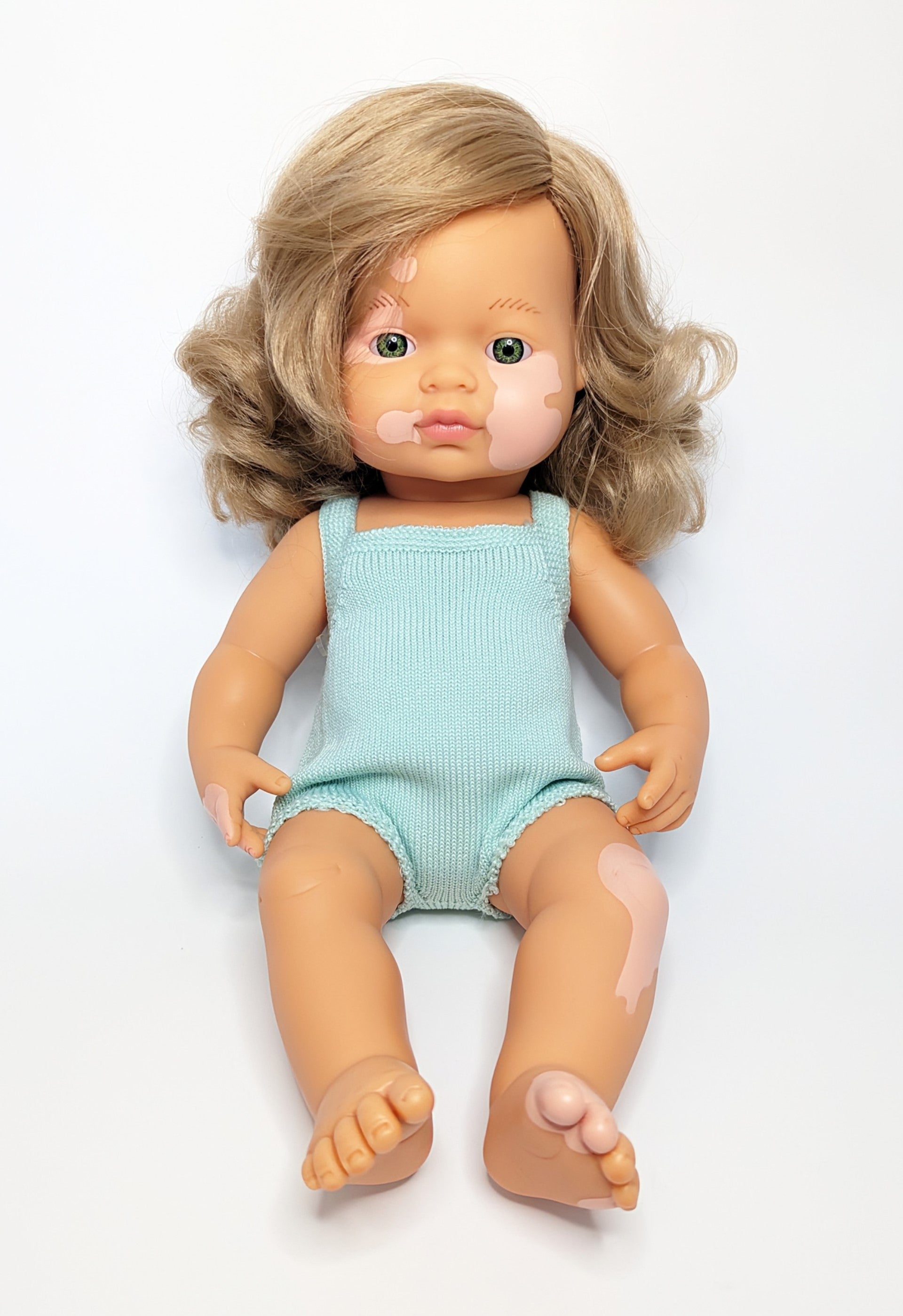 Image of Baby Doll Caucasian Dirty Blonde Girl with Vitiligo 15" Colorful Edition, wearing teal romper